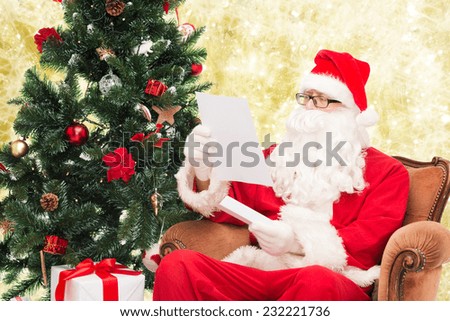 christmas, holidays and people concept - man in costume of santa claus with letter over yellow lights background