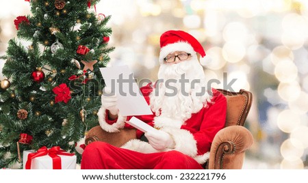 christmas, holidays and people concept - man in costume of santa claus with letter over lights background