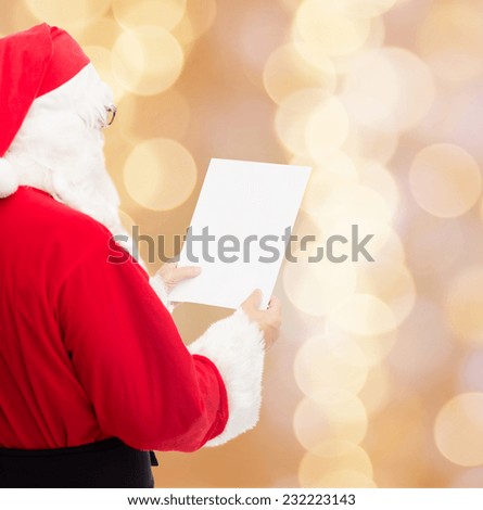 christmas, holidays and people concept - man in costume of santa claus reading letter over beige lights background