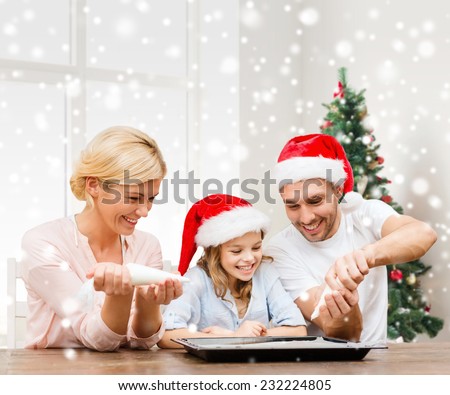 food, family, happiness, cooking and people concept - smiling family in santa helper hats glazing cookies on pan over living room and christmas tree background