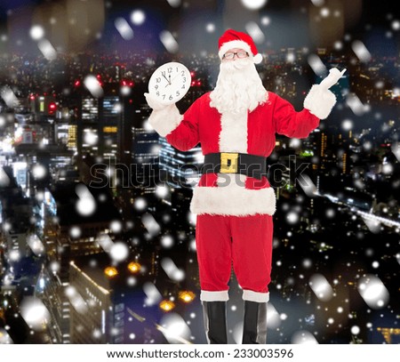 christmas, holidays and people concept - man in costume of santa claus with clock showing twelve over snowy night city background