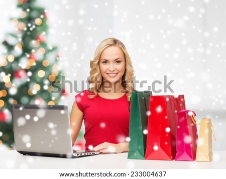 technology, holidays, e-commerce and people concept - woman with shopping bags and laptop computer over living room background