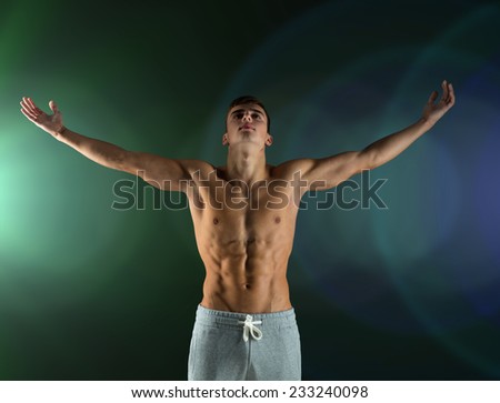 sport, bodybuilding, strength and people concept - young man standing with raised hands over dark background