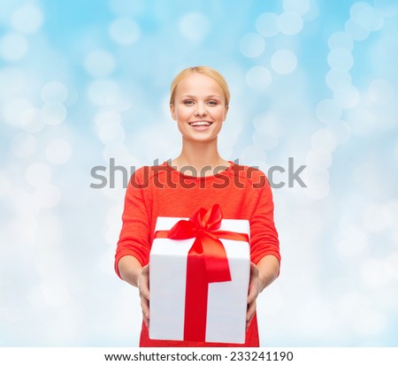 christmas, holidays, valentine's day, celebration and people concept - smiling woman in red clothes with gift box over blue lights background