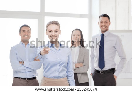 business and office concept - smiling handsome businesswoman with team in office pointing finger at you