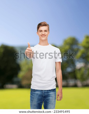 gesture, advertising, summer vacation and people concept - smiling young man in blank white t-shirt showing thumbs up over park background