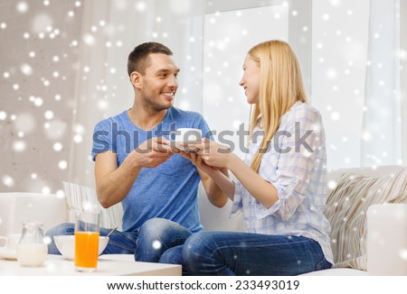 love, family, healthy food and happiness concept - smiling man giving his girlfriend or wife cup of coffee at home