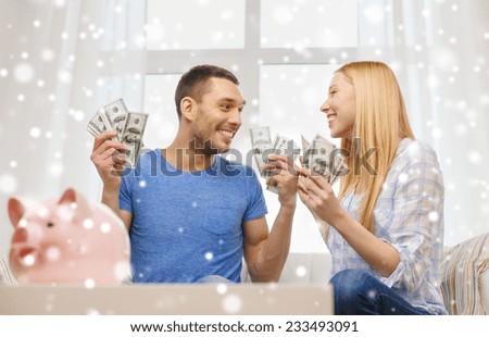 love, family, finance, money and happiness concept - happy couple with cash money and piggybank cheering at home