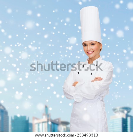 christmas, cooking, holidays and people concept - smiling female chef, cook or baker dreaming over blue snowy sky and city background background