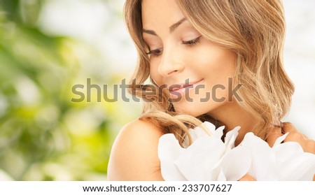 beauty, people and health concept - beautiful young woman with flowers and bare shoulders over green background