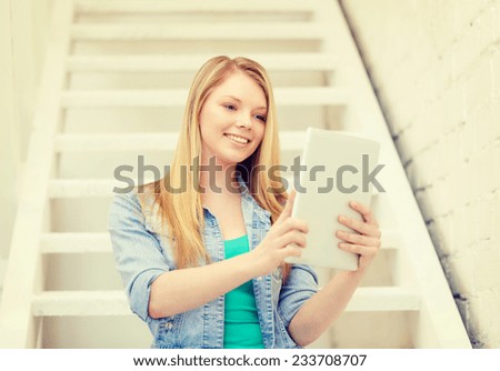 education and technology concept - smiling female student with tablet pc computer sitting on staircase