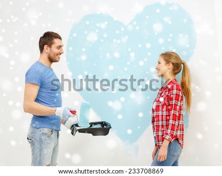 repair, building, love, people and home concept - smiling couple painting big heart on wall at home