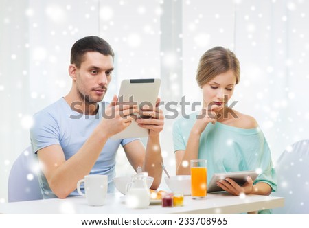 food, family, people and technology concept - couple with tablet pc computers reading news and having breakfast at home