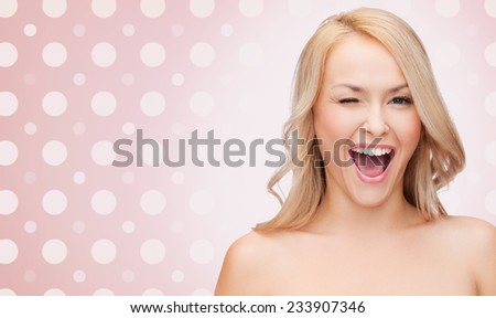 people and beauty concept - beautiful smiling young woman winking one eye over pink and white polka dot pattern background