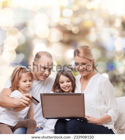 family, holidays, shopping, technology and people - happy family with laptop computer and credit card over lights background