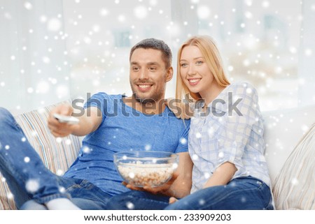 love, family, technology, entertainment and people concept - smiling couple watching tv and lying on sofa at home