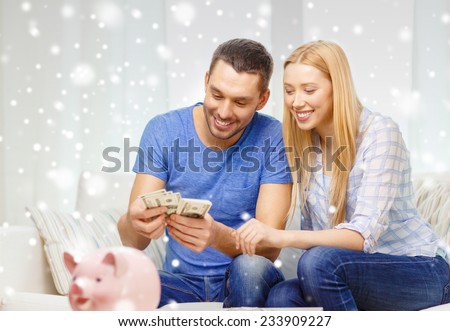 love, family, finance, money and happiness concept - smiling couple counting money with piggybank on table at home