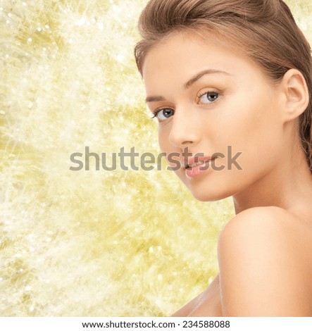beauty, people and health concept - beautiful young woman with bare shoulders and long wavy hair over yellow lights background