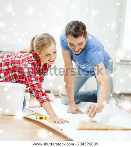 repair, building, teamwork and home concept - smiling couple smearing wallpaper with glue
