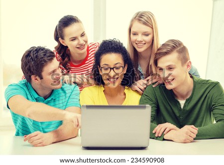 education, technology and college concept - five smiling students looking at laptop at school