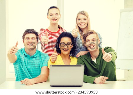 education and college concept - five smiling students with laptop at school showing thumbs up