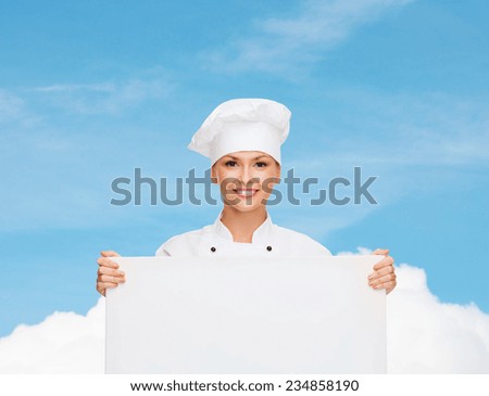 cooking, advertisement and people concept - smiling female chef, cook or baker with white blank board over blue sky with cloud background