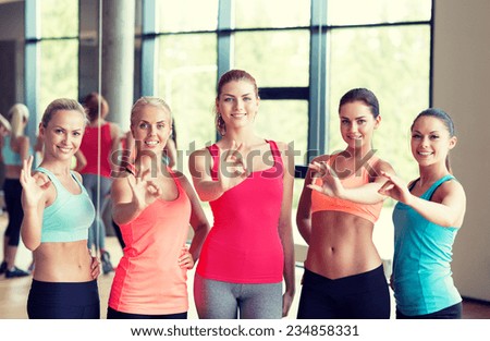 fitness, sport, friendship and lifestyle concept - group of women showing ok sign in gym