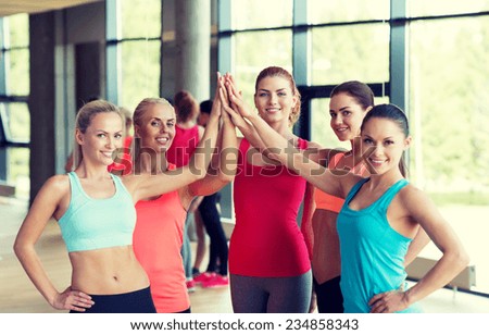 fitness, sport, friendship and lifestyle concept - group of women making high five gesture in gym