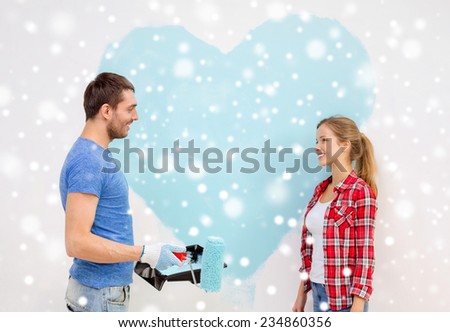 repair, building, love, people and home concept - smiling couple painting big heart on wall at home