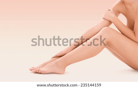 healthcare, beauty and people concept - beautiful woman touching her bare legs over pink background