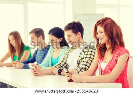 education, relationships and technology concept - group of smiling students with smartphones at school