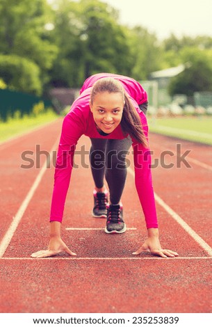 fitness, sport, training and lifestyle concept - smiling african american woman running on track outdoors
