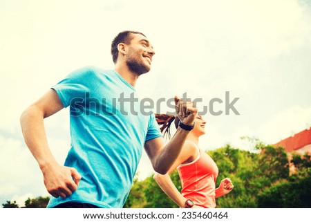 fitness, sport, friendship and lifestyle concept - smiling couple running outdoors
