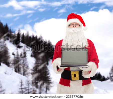 christmas, advertisement, technology, and people concept - man in costume of santa claus with laptop computer over snowy mountains background