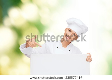 cooking, advertisement and people concept - smiling female chef, cook or baker pointing finger to white blank board over green background