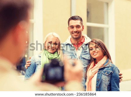 travel, vacation, technology and friendship concept - guy picturing group of friends in city