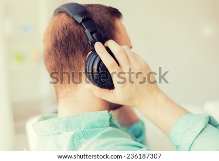 technology, music, leisure and happiness concept - close up of man in headphones at home from back