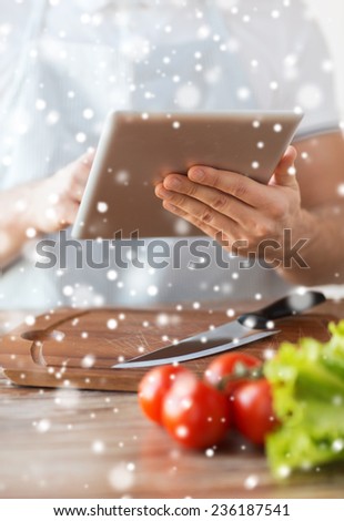 cooking, people, technology and home concept - closeup of man reading recipe from tablet pc computer and vegetables on table in kitchen
