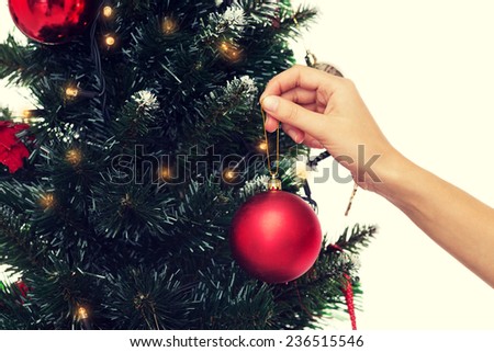 winter holidays, celebration and people concept - close up of woman decorating christmas tree with ball