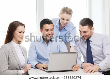 business, teamwork and office concept - smiling business team working with laptop computer in office