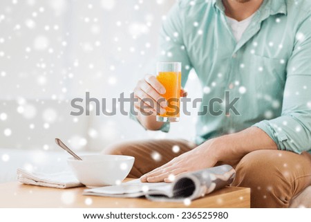 home, news, food, drinks and people concept - close up of man reading magazine and drinking juice at home