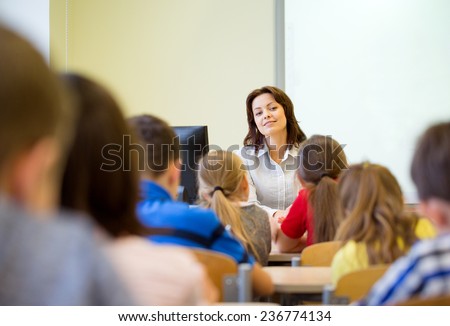 education, elementary school, learning and people concept - group of school kids with teacher sitting in classroom