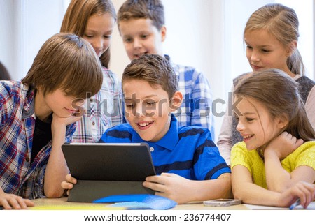 education, elementary school, learning, technology and people concept - group of school kids with tablet pc computer having fun on break in classroom