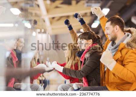 people, friendship, sport and leisure concept - happy friends watching hockey game or figure skating performance on skating rink