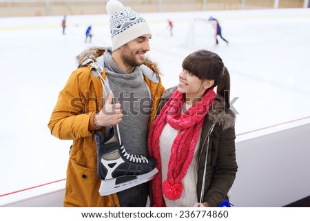 people, friendship, sport and leisure concept - happy couple with ice-skates on skating rink
