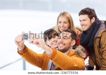 people, friendship, technology and leisure concept - happy friends taking selfie with digital camera on skating rink