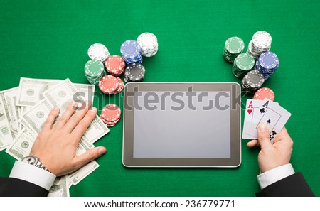 casino, online gambling, technology and people concept - close up of poker player with playing cards, tablet pc computer and chips at green casino table