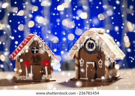 holidays, christmas, baking and sweets concept - closeup of beautiful gingerbread houses on table over blue garland lights