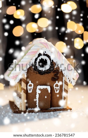 holidays, christmas, baking and sweets concept - closeup of beautiful gingerbread house on table over black garland lights
