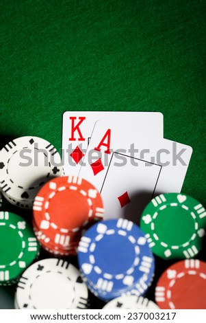 gambling, fortune, game and entertainment concept - close up of casino chips and playing cards on green table surface
